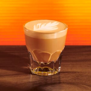 Starbucks hot honey cortado in a small glass on an orange background