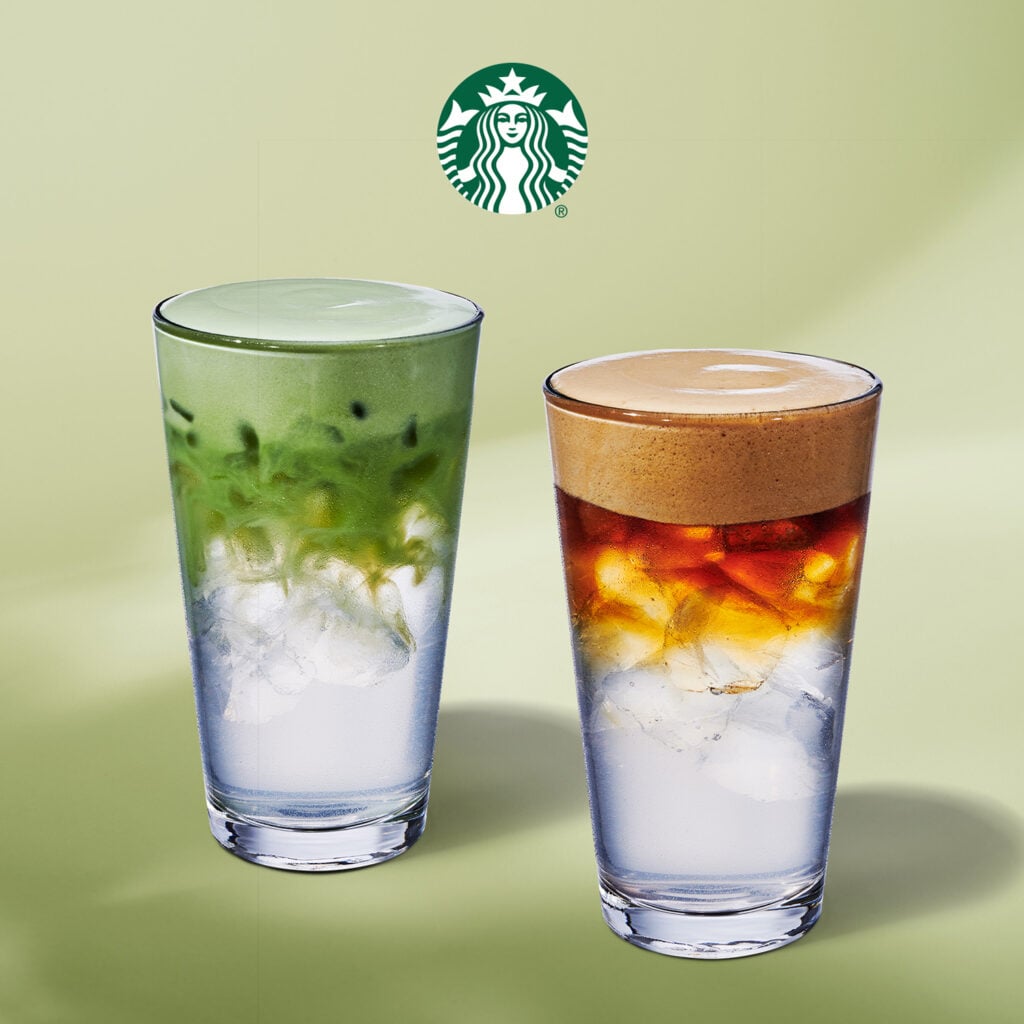 Two tall glasses of beverages are displayed. The left glass contains a green drink with a frothy top, while the right glass features a layered iced coffee with a creamy brown foam on top. Both drinks are served over ice against a soft green background.