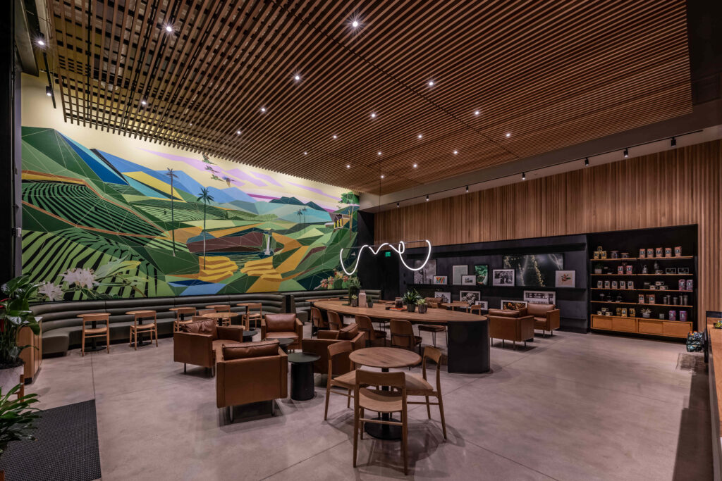 A modern interior featuring a vibrant mural of geometric landscapes. Leather seating and wooden tables create a cozy atmosphere.
