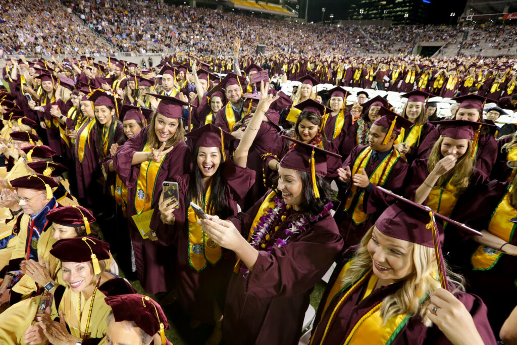 A lively graduation ceremony scene with graduates in maroon caps and gowns, celebrating joyfully, taking photos, and cheering.