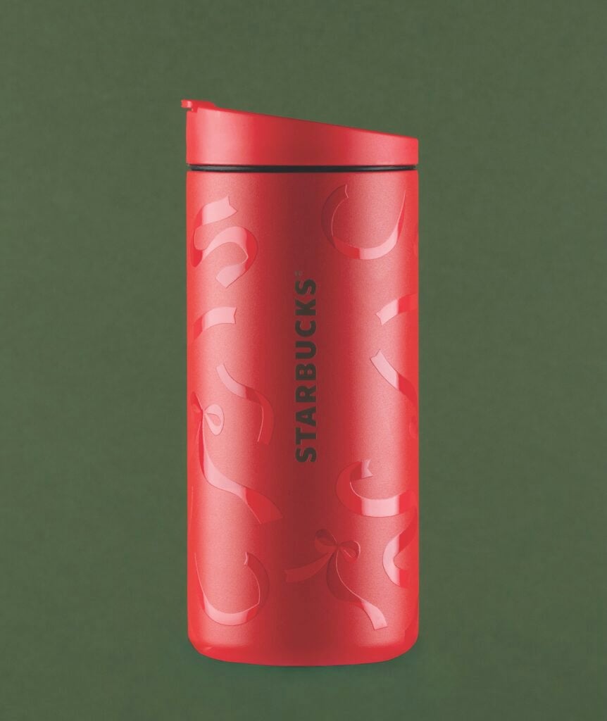 A red Starbucks travel mug with a smooth finish and a lid, featuring a decorative ribbon design and the Starbucks logo.