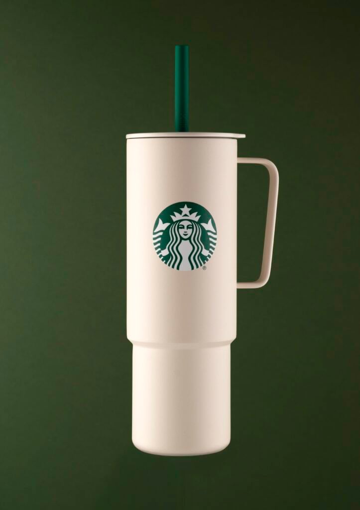 A white tumbler with a green straw and a Starbucks logo, set against a dark green background.