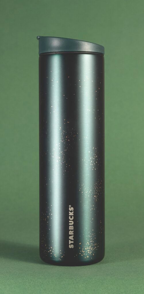 A sleek, metallic water bottle with a dark finish, featuring scattered specks of a lighter color. The background is a soft green.