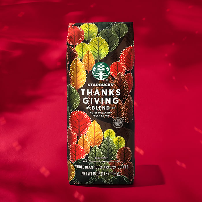 A bag of Starbucks Thanksgiving Blend coffee featuring a colorful leaf design. It highlights notes of candied pecan and sage.