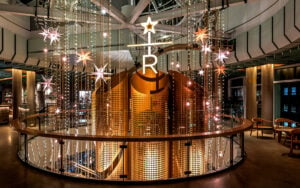 A modern interior features a striking golden structure with perforated designs, adorned with star-shaped lights and hanging decorations.