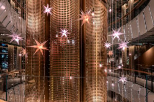 Stylish interior featuring large, perforated golden columns adorned with hanging star-shaped lights in various colors.