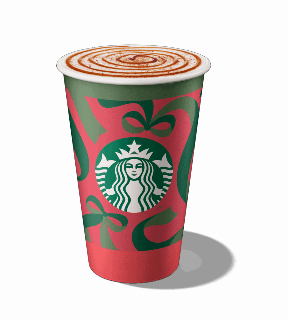 A festive Starbucks cup featuring a red and green design with bows, topped with whipped cream and a cinnamon swirl.
