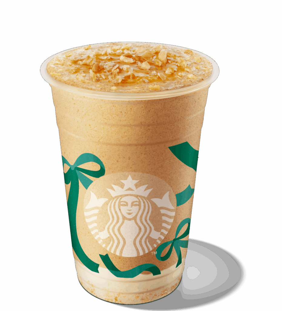 A frosty beverage in a clear cup, topped with caramel drizzle and crunchy oat pieces, featuring the Starbucks logo and festive green ribbons.
