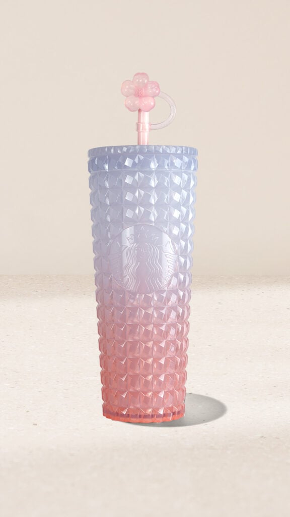 A gradient tumbler featuring a diamond pattern, transitioning from light blue at the top to pink at the bottom, topped with a flower-shaped straw.