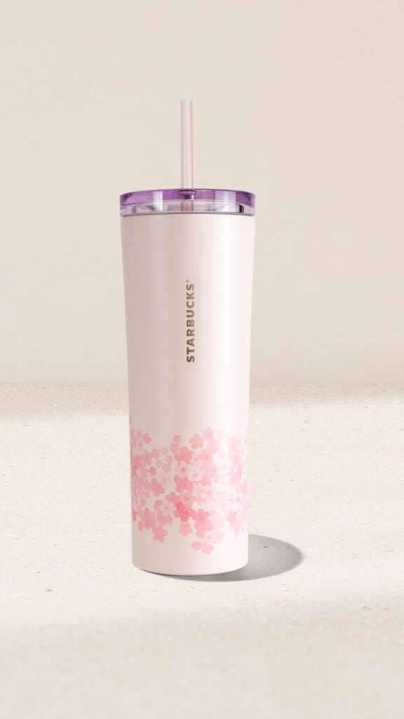 A pink Starbucks tumbler with a floral design at the base and a purple lid. It features a reusable straw and a sleek finish.