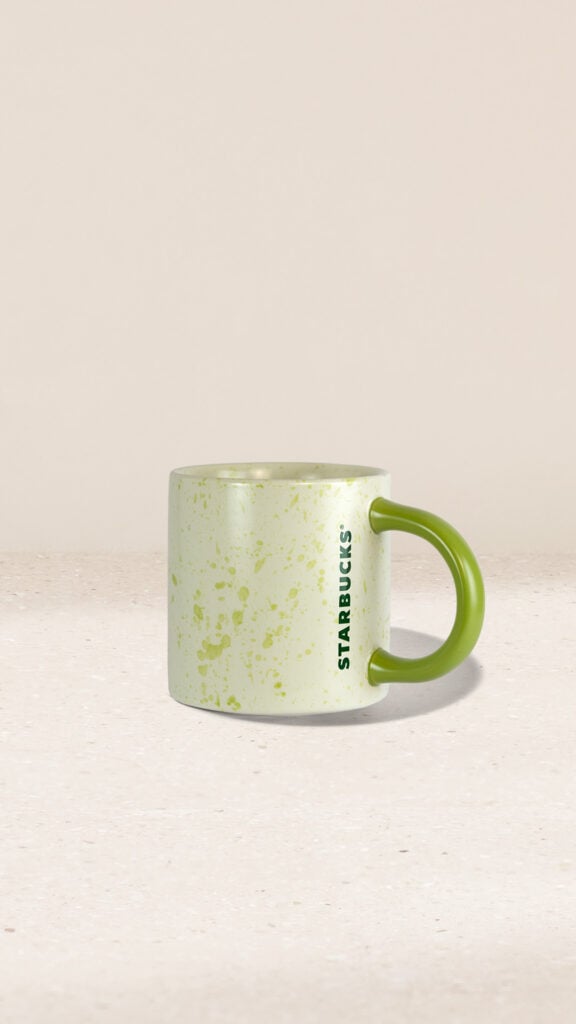 A light green speckled mug with a contrasting green handle, featuring the Starbucks logo in dark green.