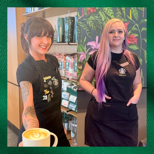 Two baristas are featured, one on the left holding a latte and smiling, wearing a black apron with colorful designs. The other on the right has long hair with purple highlights, also in a black apron, standing against a floral backdrop.
