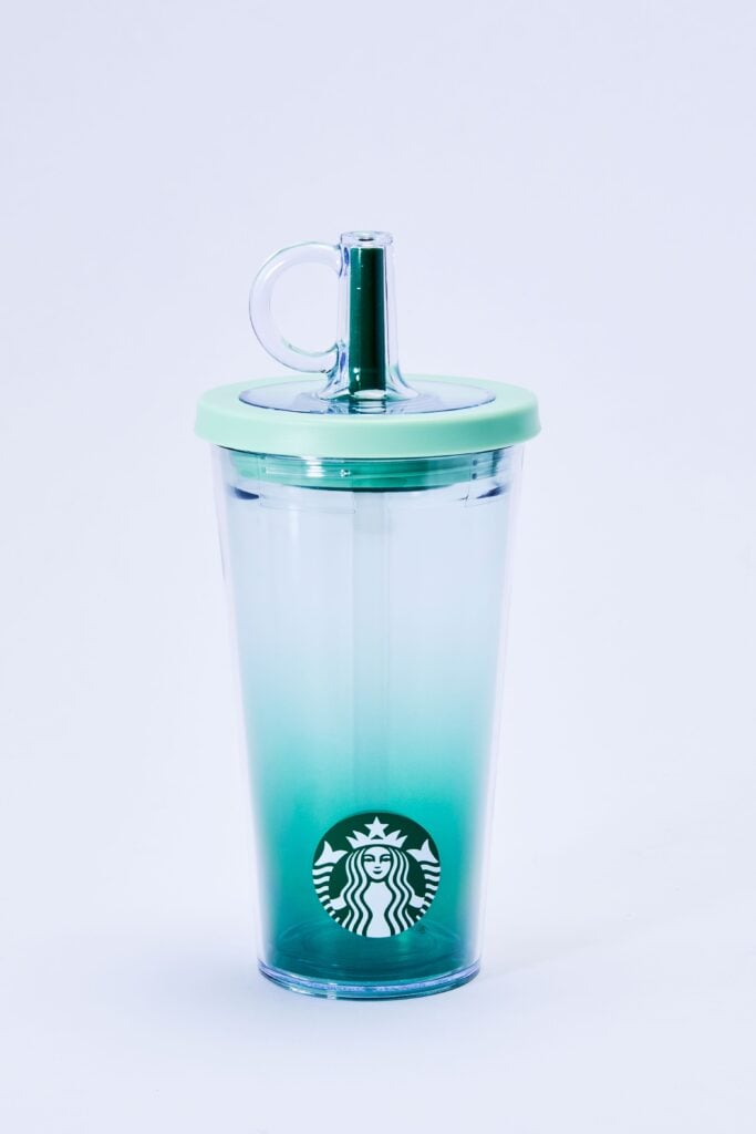 A clear tumbler with a gradient from light to dark green, featuring a mint green lid and a straw, with the Starbucks logo at the bottom.