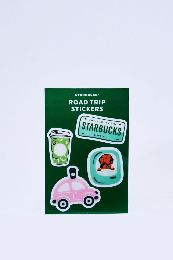 A green sheet features various colorful stickers, including a pink car, a coffee cup, and a dog in a window, labeled "Starbucks Road Trip Stickers.