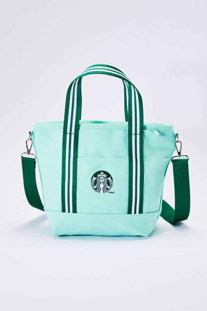 A mint green tote bag with dual green and white striped handles, featuring a front pocket and a Starbucks logo.