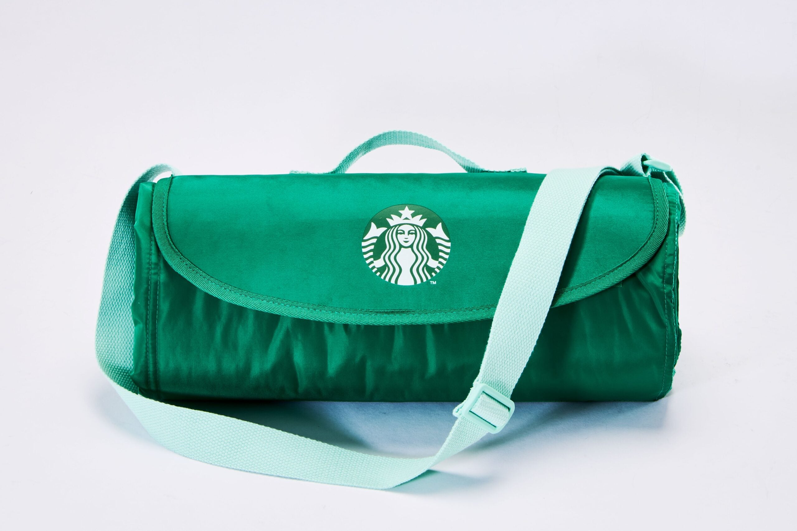A green bag with a flap and a shoulder strap, featuring the Starbucks logo prominently on the front.