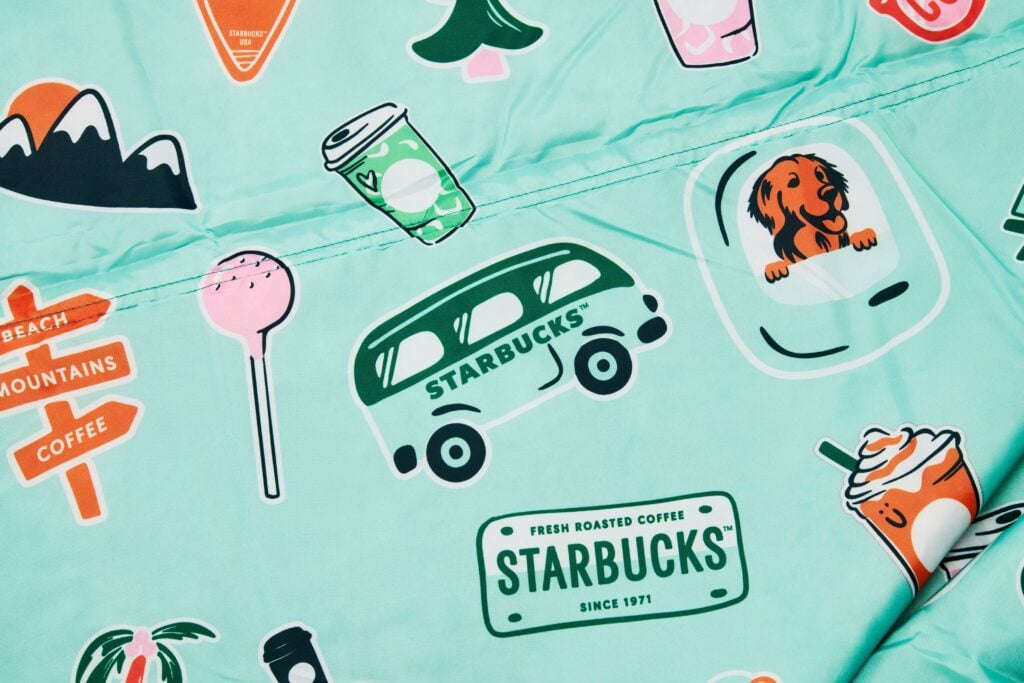 A mint green fabric covered in various colorful Starbucks-themed stickers, including coffee cups, a van, and playful icons.