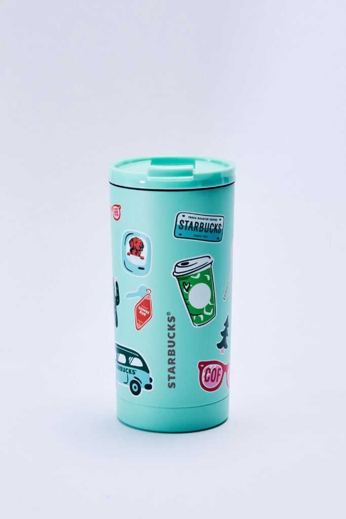 A turquoise Starbucks travel mug adorned with various colorful stickers, including coffee cups, a dog, and a car.