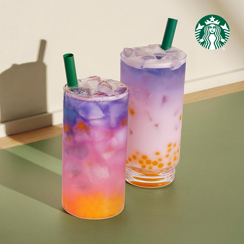 Two colorful drinks with ice, featuring vibrant layers of purple, pink, and orange, topped with green straws.