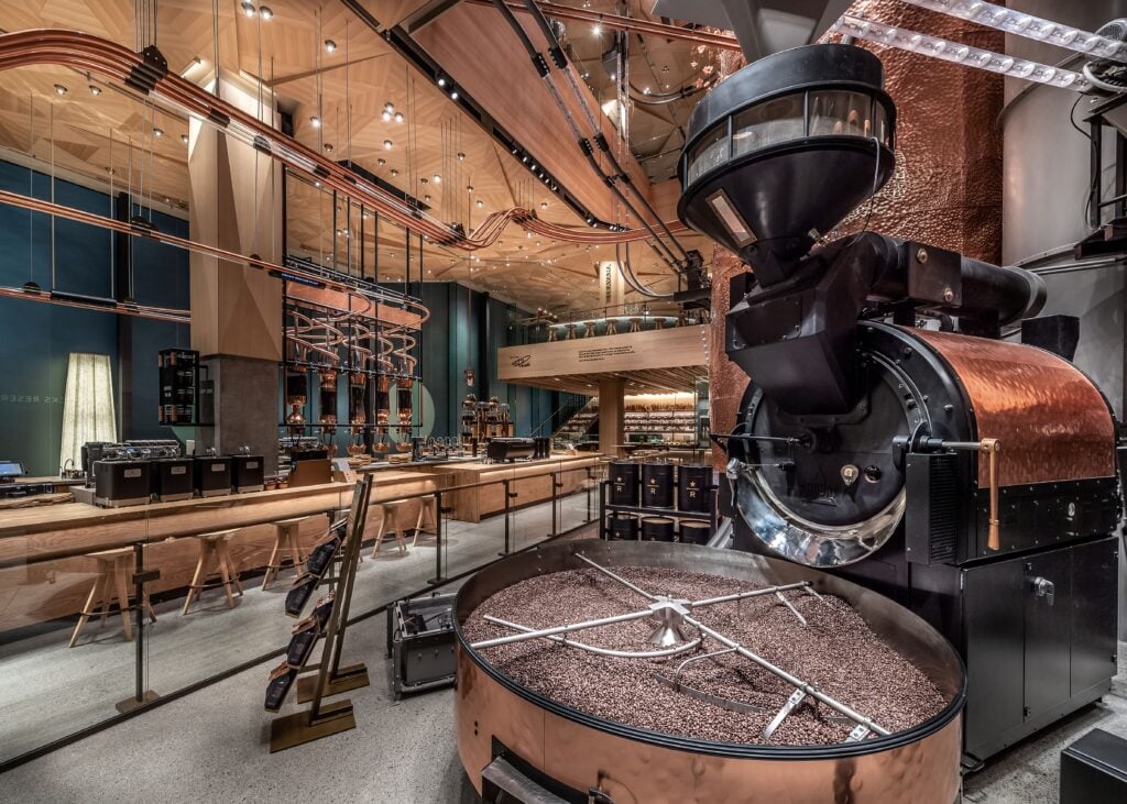 A modern coffee roasting facility featuring a large copper roasting machine, wooden counters, and sleek industrial design elements.