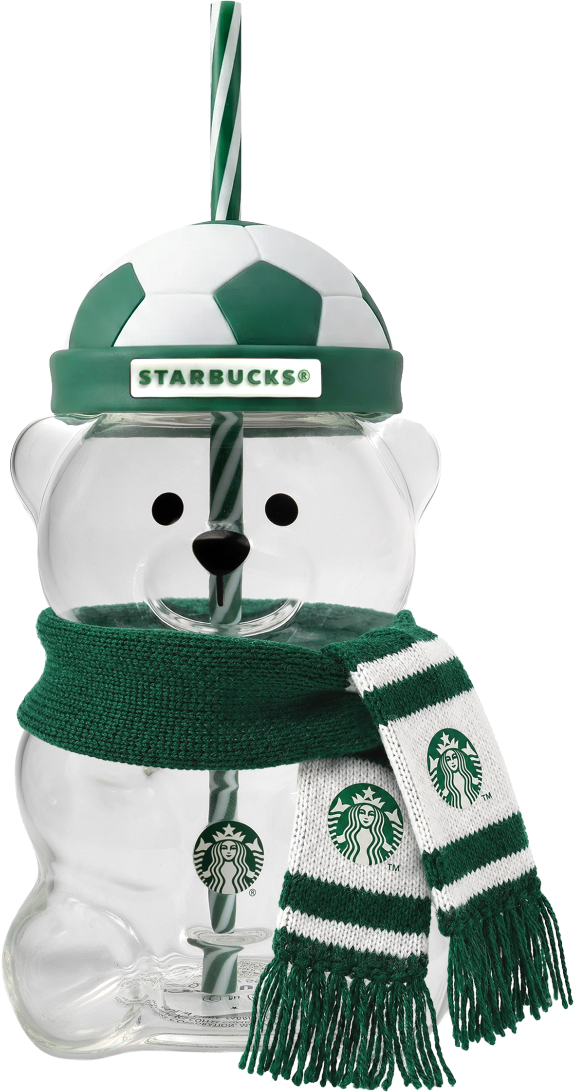 A clear bear-shaped cup features a soccer ball lid and a green and white striped straw. It wears a knitted scarf with fringe.