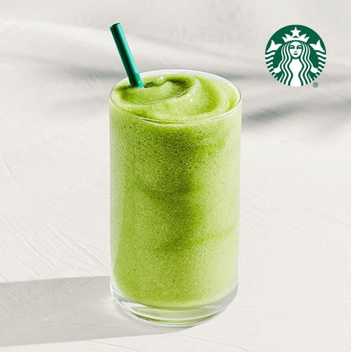 A tall glass filled with a smooth, vibrant green beverage, topped with a green straw, sits on a light surface.