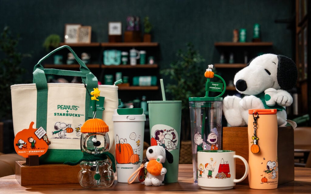 A collection of merch from the Starbucks Peanuts collaboration including a tote bag, mugs, and a snoopy plush