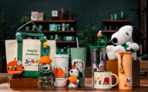 A collection of merch from the Starbucks Peanuts collaboration including a tote bag, mugs, and a snoopy plush