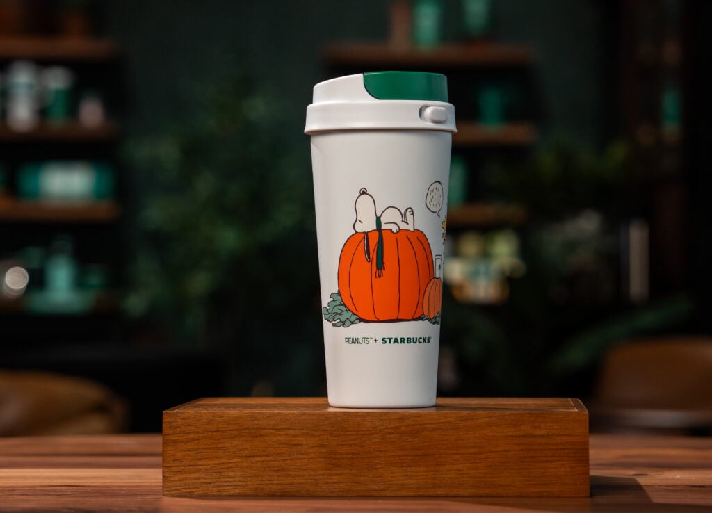 A white Coffee tumbler with Snoopy laying on a pumpkin